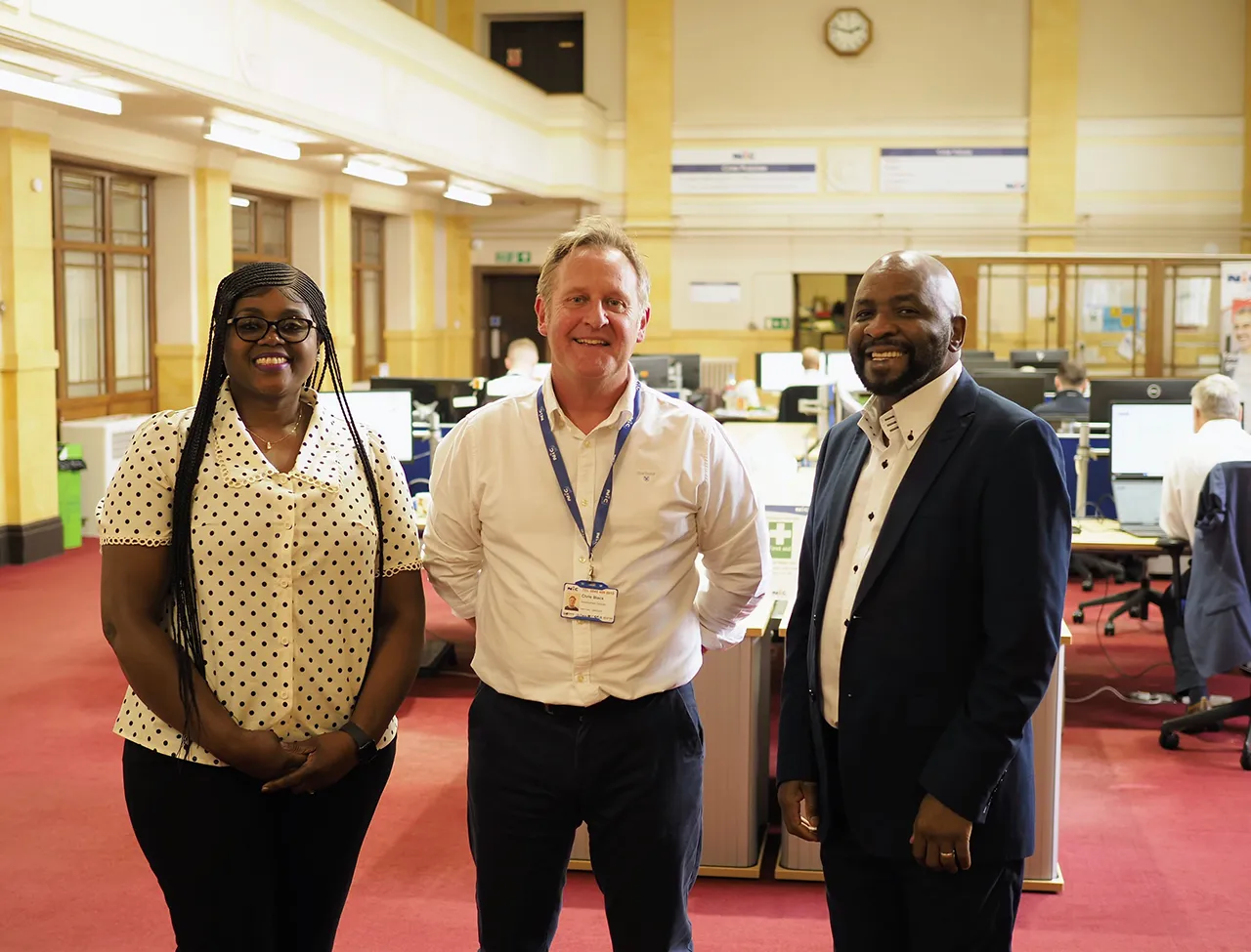 Edmack and Memory Kamhuka with Chris Black from NIC Local, standing together in an office